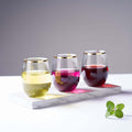 Three colorful drinks in elegant glasses on a marble tray with mint leaves.